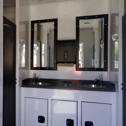 Interior of our 8-station shower trailer featuring a double vanity with mirrors