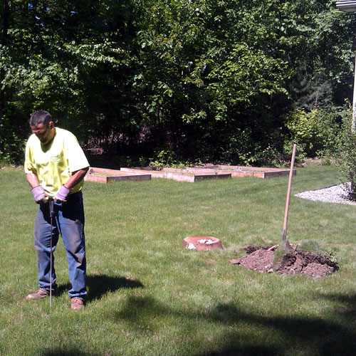 Stone septic technician using a probe to locate buried components of the septic system during an inspection.